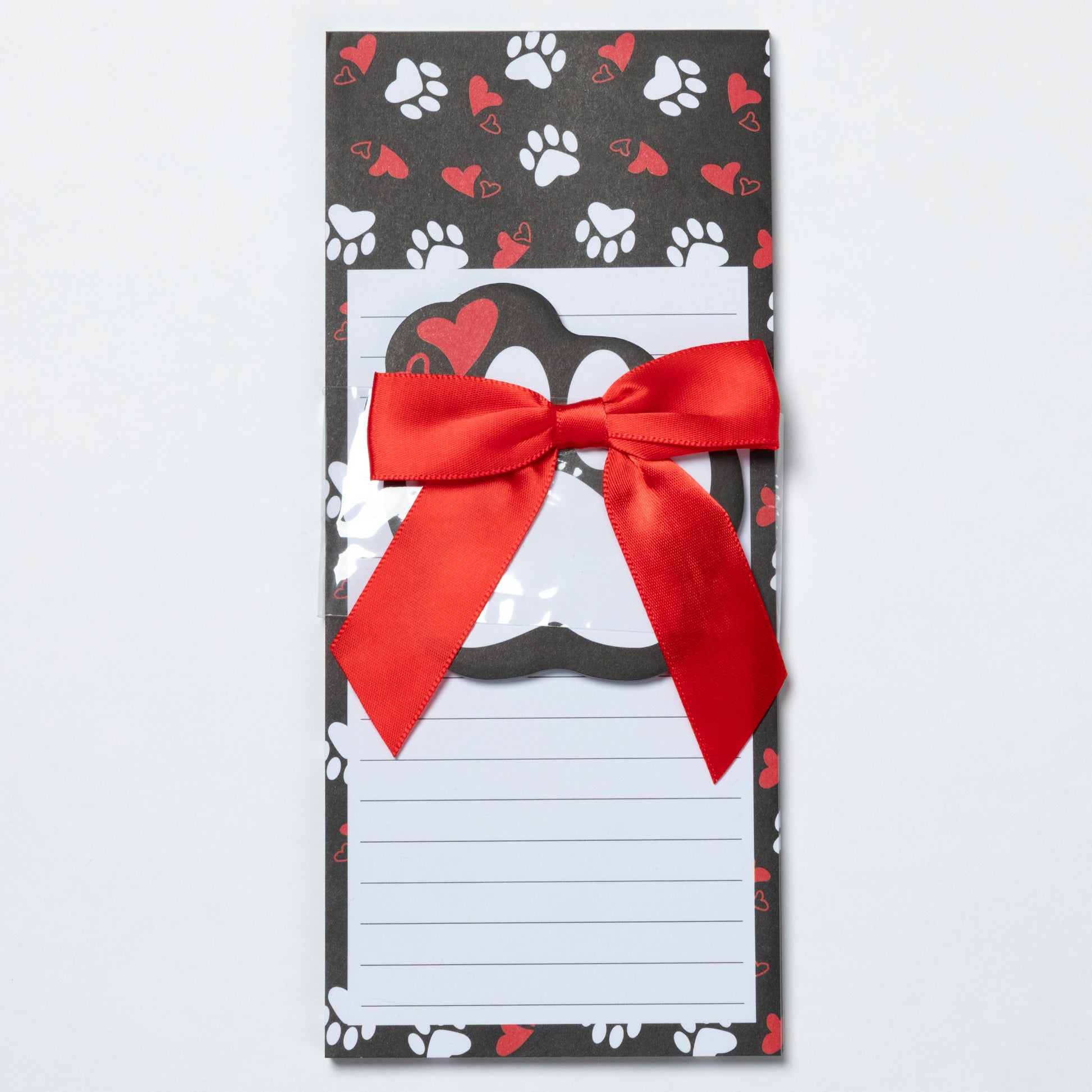 Notepad with a red ribbon on a black background with paw and heart patterns