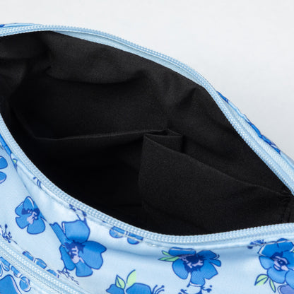 Close-up of an open light blue zippered pouch with a blue floral print and a black fabric interior.