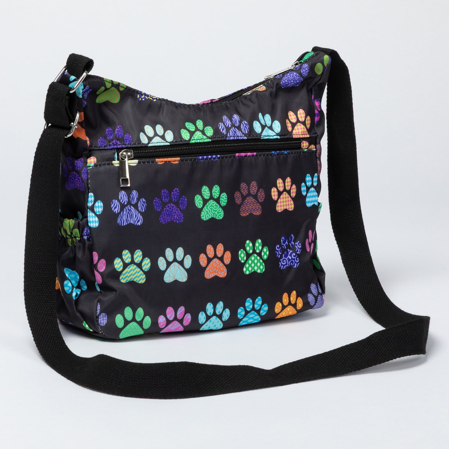 A black nylon shoulder bag with a colorful dog paw print pattern, featuring a front zippered pocket and a black adjustable shoulder strap, shown on a light gray background.