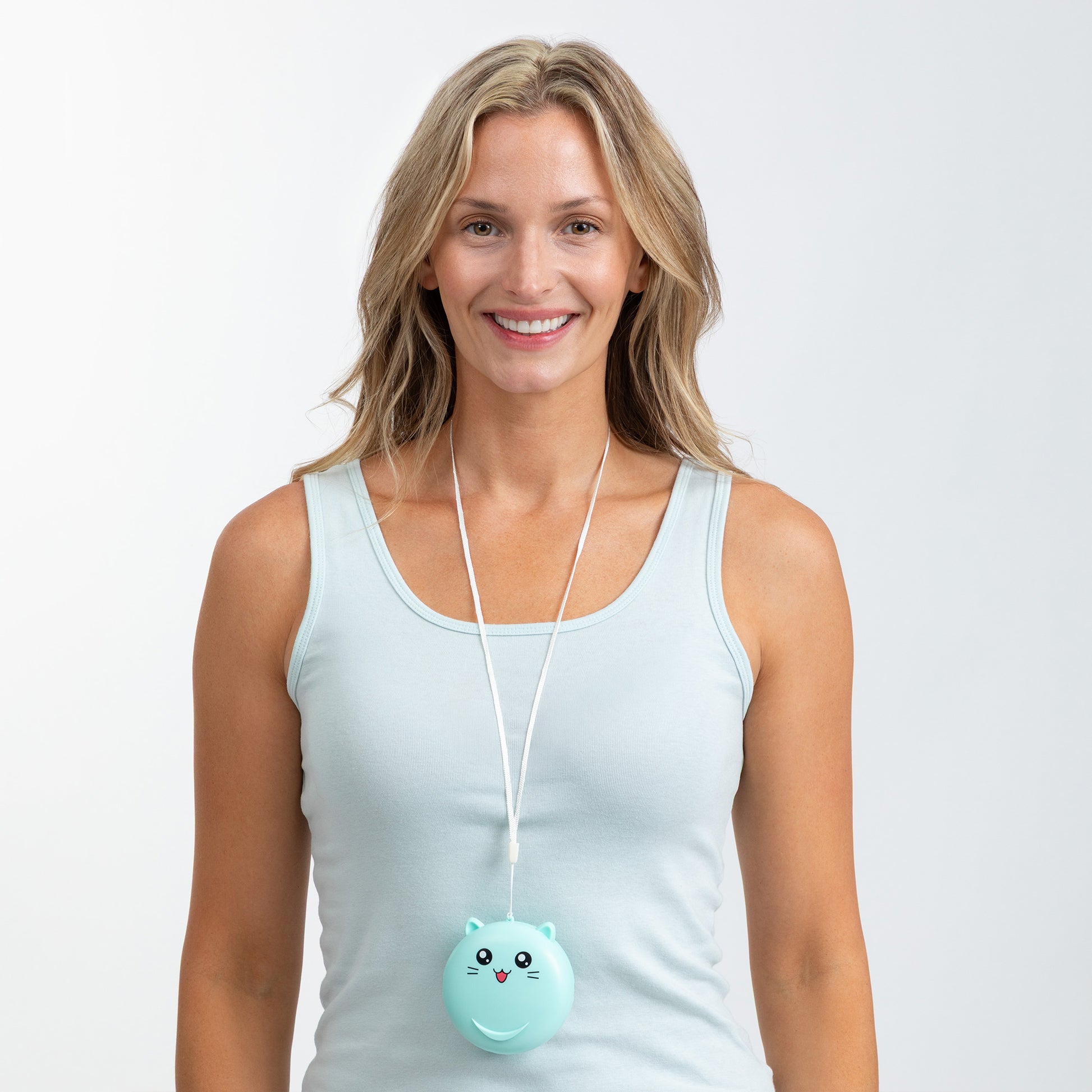 A smiling woman wearing a light blue tank top and a white cord necklace with a round mint-green cat-shaped mini fan, set against a plain light gray studio background.