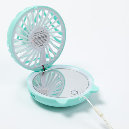A mint green and white portable handheld fan with an integrated mirror inside the base, shown open on a white background.
