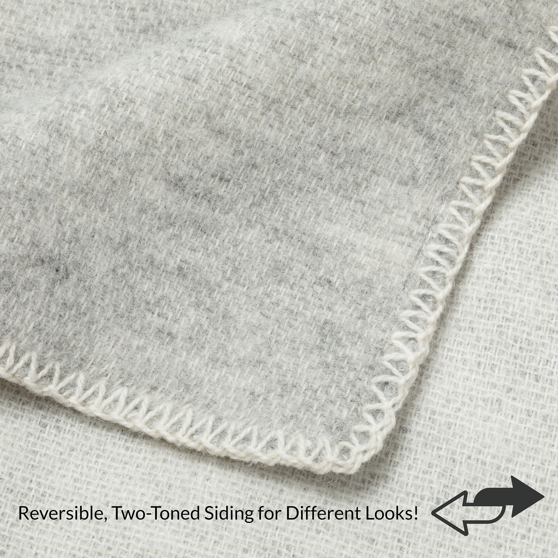 Close-up of a light gray heathered fabric corner with white zigzag stitching, showing reversible two-toned sides with text and arrow overlay.