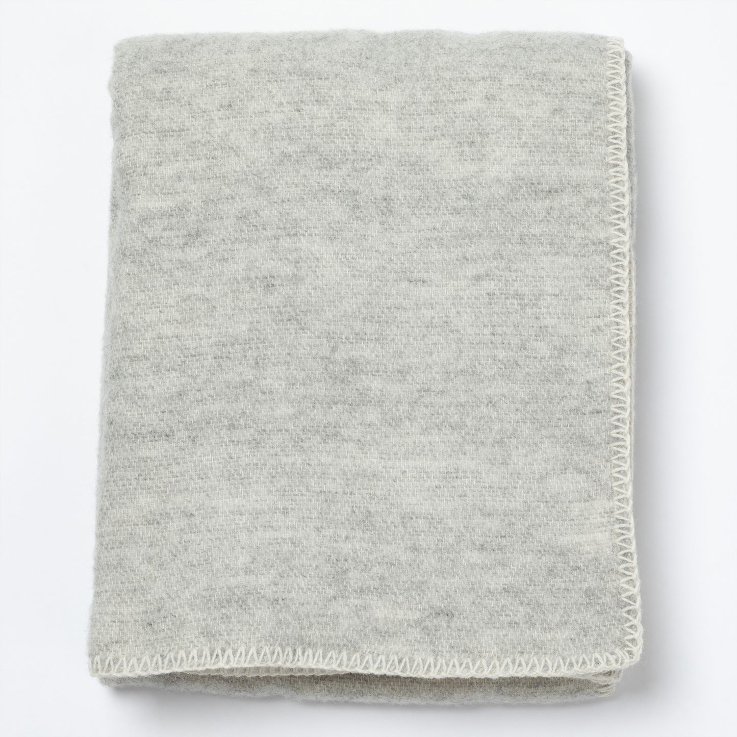 A folded light gray knit blanket with a textured heathered surface and a visible whipstitch border, shown on a plain white background.