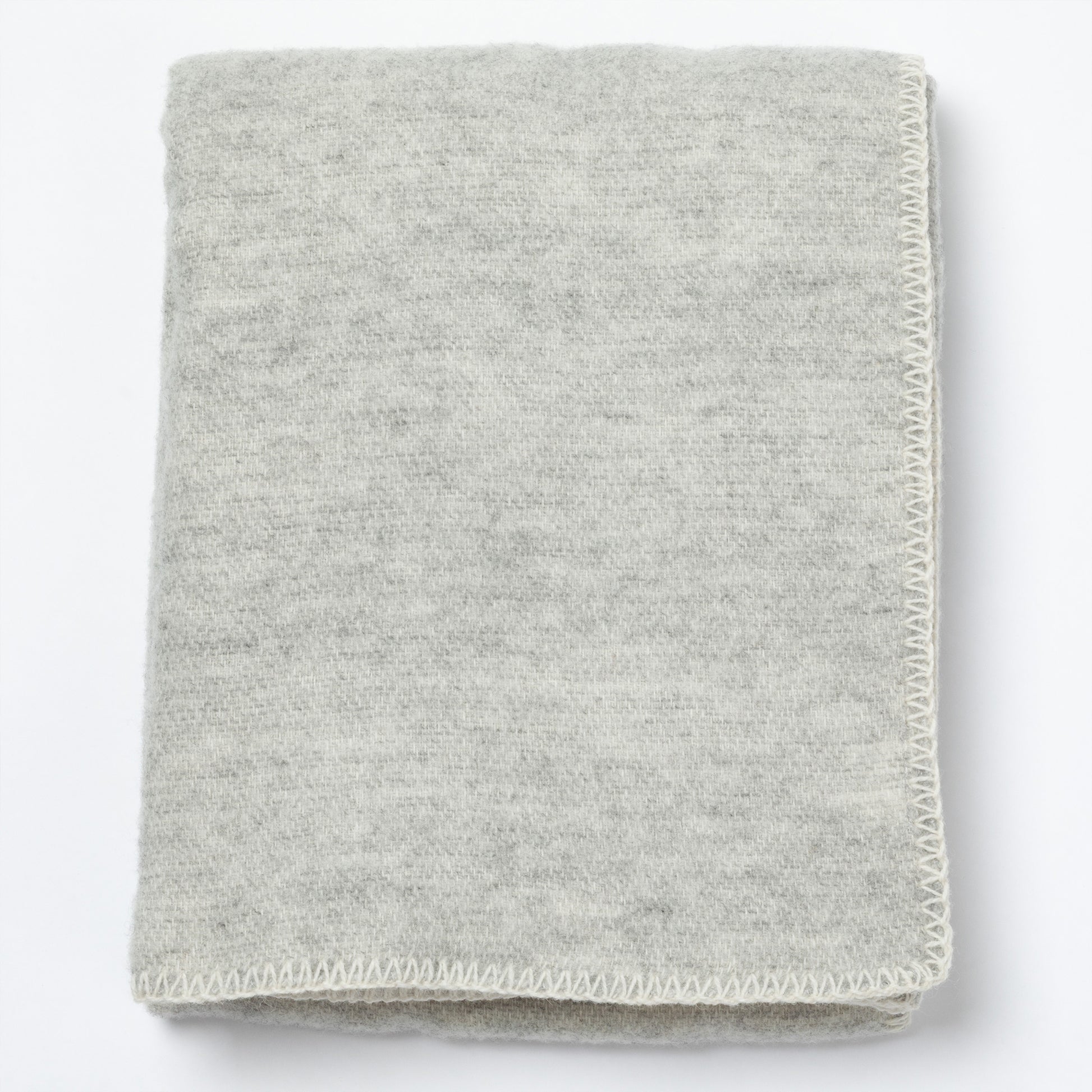 A folded light gray knit blanket with a textured heathered surface and a visible whipstitch border, shown on a plain white background.