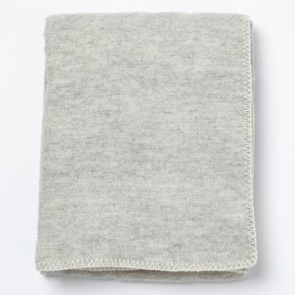 A folded light gray knit blanket with a textured heathered surface and a visible whipstitch border, shown on a plain white background.