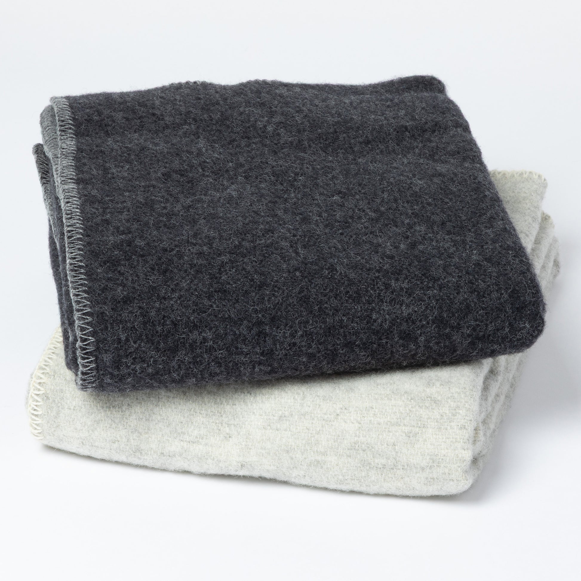 Two folded textured blankets, one dark charcoal gray and one light heather gray, stacked on a white background.