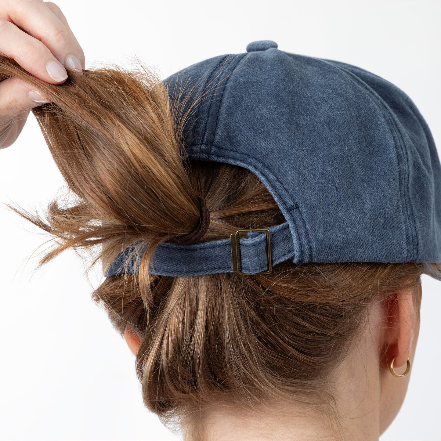 Person wearing a blue cap with hair tied up, on a white background