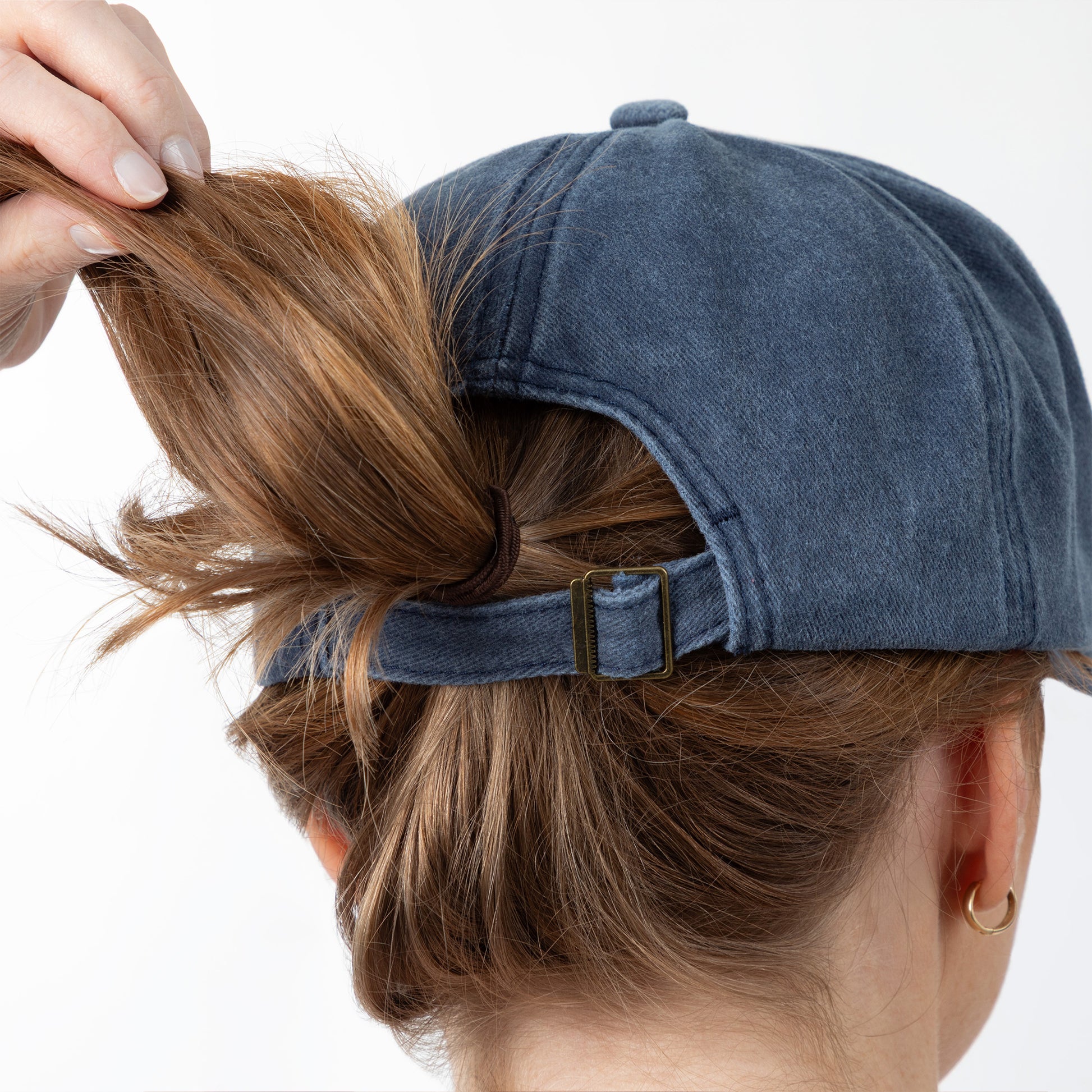 Person wearing a blue cap with hair tied up, on a white background