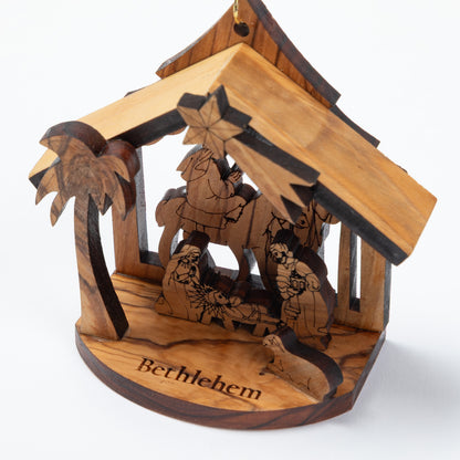 Personalized wooden nativity scene ornament featuring a stable with a palm tree, carved figures, and the word 'Bethlehem' engraved on the base, shown on a white background.