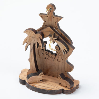 Handcrafted wooden nativity scene ornament featuring a stable with palm tree, star, baby Jesus, Mary, Joseph, and animals, shown on a white background.