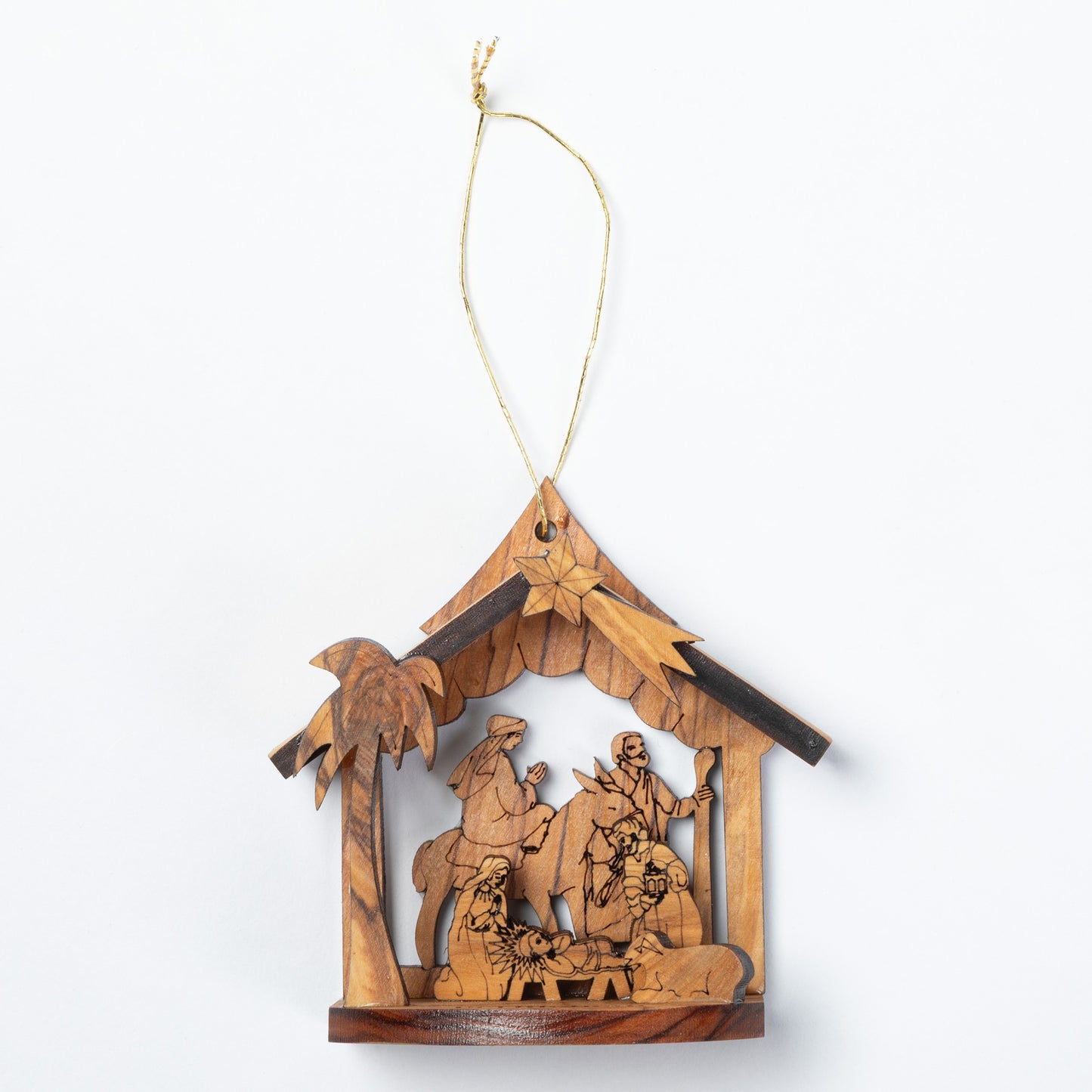 A handcrafted wooden nativity scene ornament hanging from a thin string. The ornament features a house-shaped frame with a star at the peak, carved figures of the Holy Family, animals, and a palm tree, all made from light and dark natural wood tones.