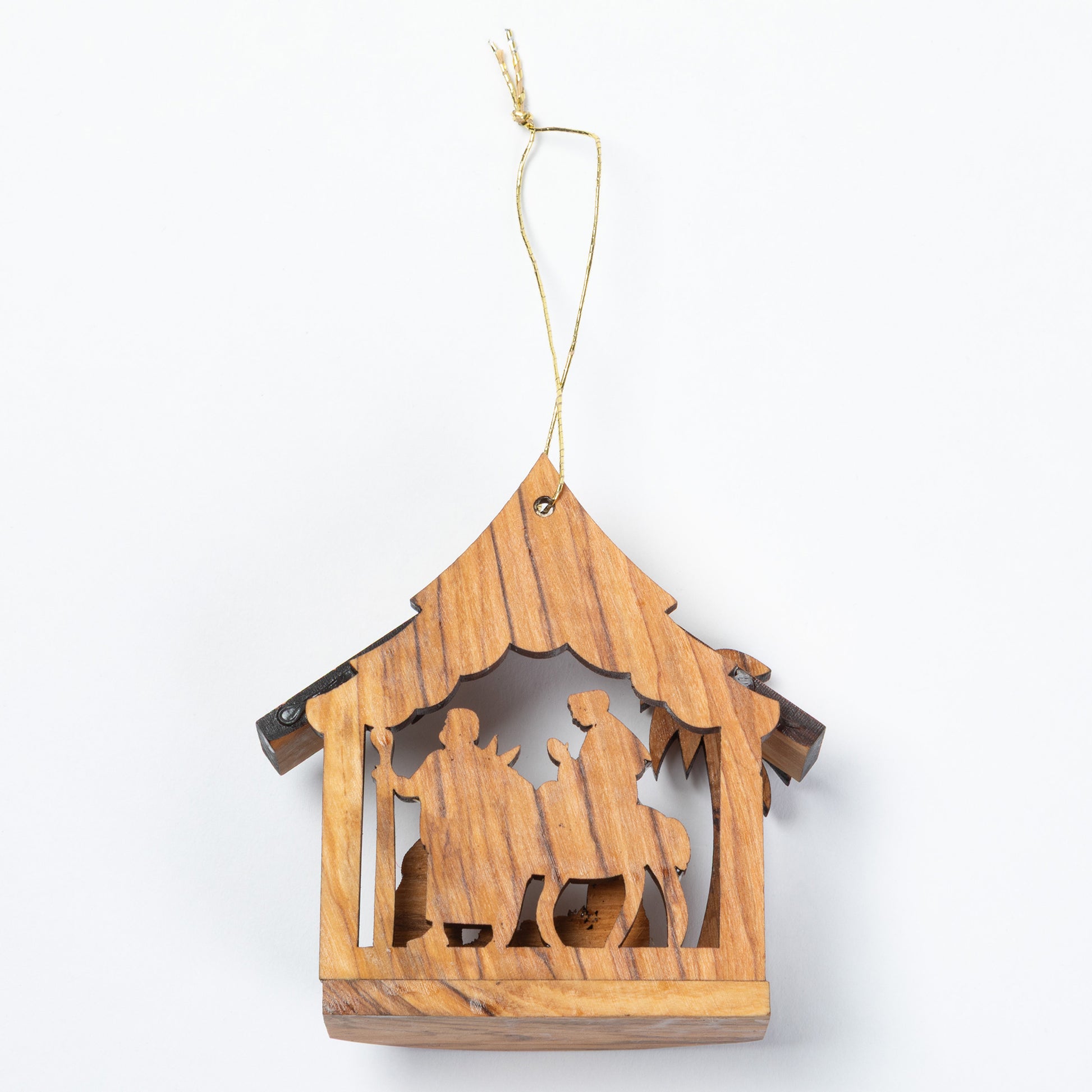 A small wooden hanging nativity ornament with a house-shaped frame and cutout figures, suspended by a thin string on a plain white background.