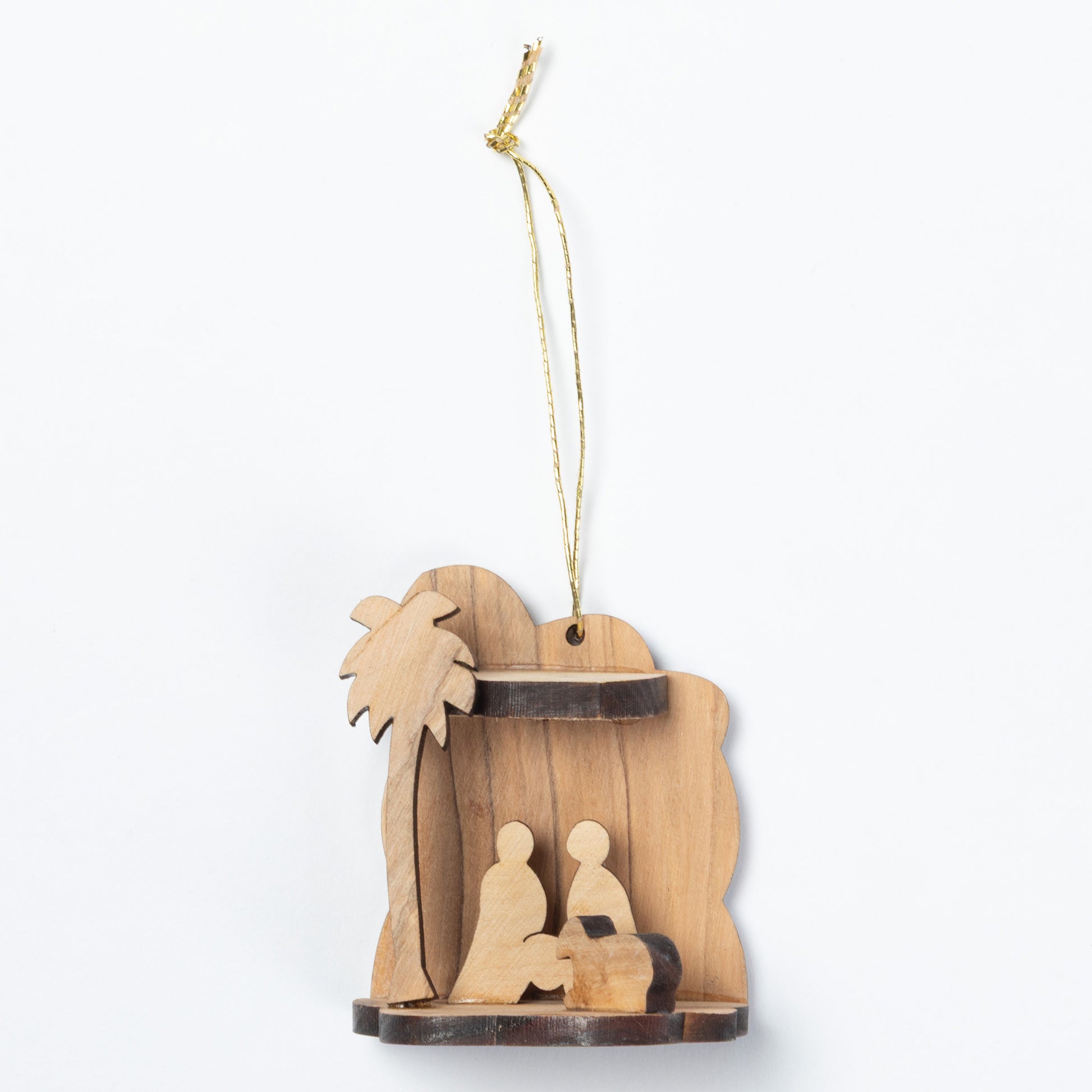 A small wooden nativity scene ornament hanging from a gold string, featuring a palm tree and two seated figures on a white background.