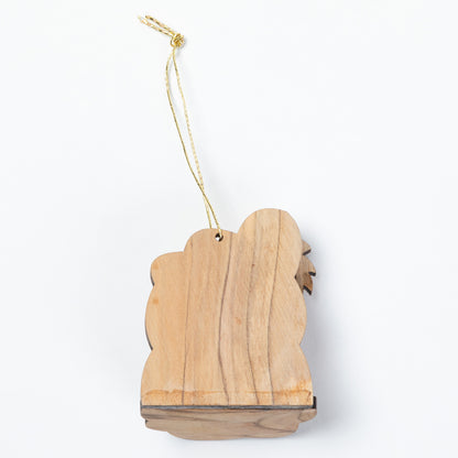 The back of an olive wood ornament, hanging from a thin gold string against a plain white background.