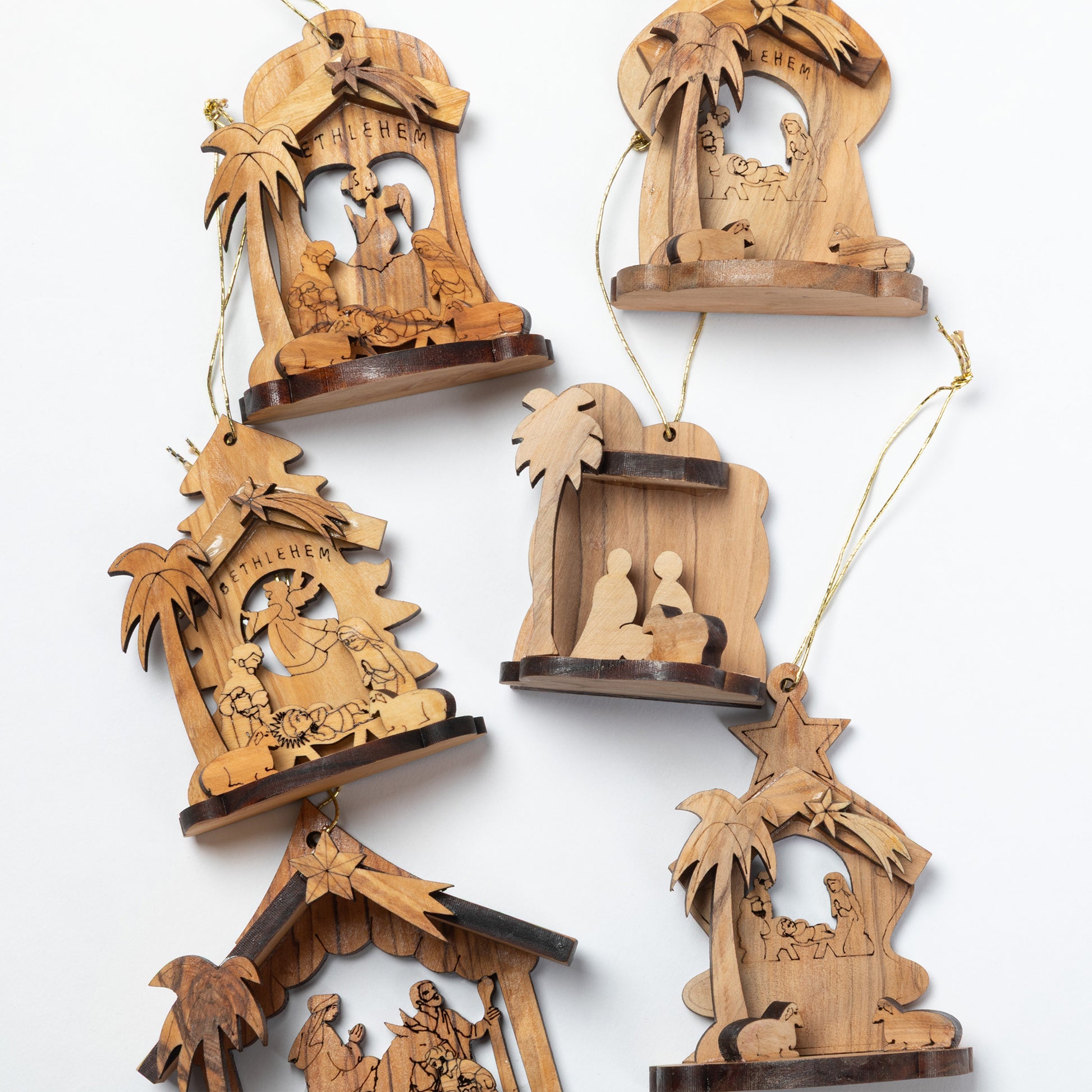 Six hand-carved wooden Christmas nativity ornaments in various designs, displayed on a clean white background.