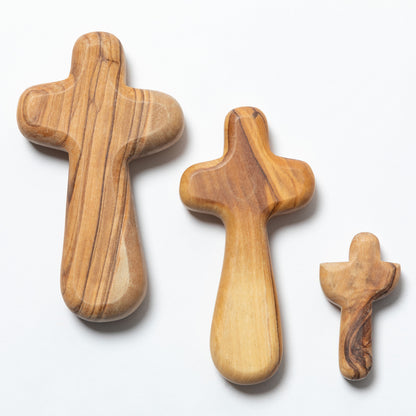 Three olive wood crosses in different sizes arranged diagonally on a clean white background.