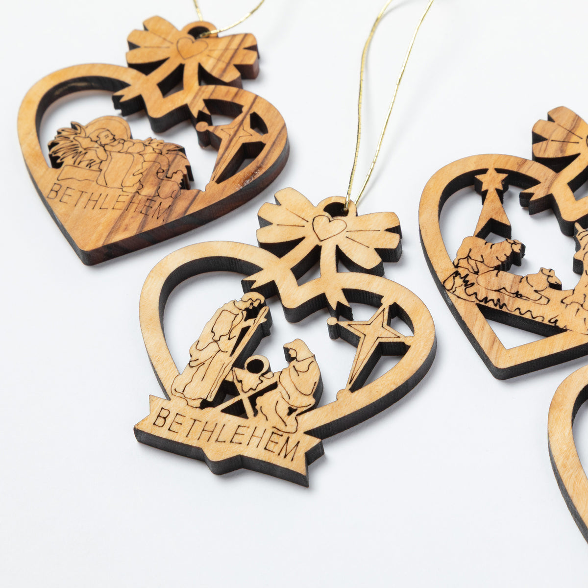 Close-up of wooden heart-shaped hanging ornaments with laser-cut nativity scenes and the word BETHLEHEM, shown on a white background.
