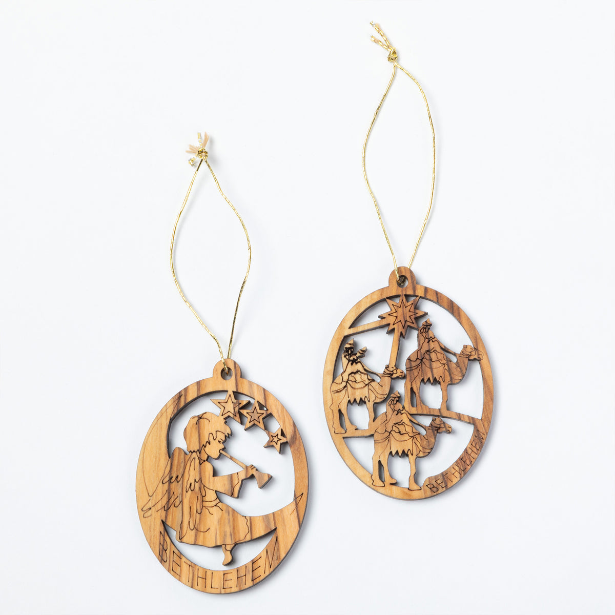 Two oval wooden Christmas ornaments with laser-cut nativity scenes, hanging from light tan strings against a plain white background.