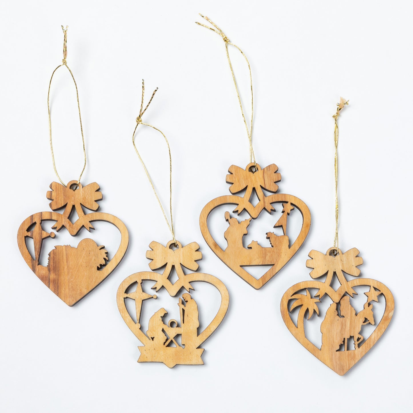 The back of four laser cut olive wood ornaments, featuring hearts filled with nativity scene imagery.