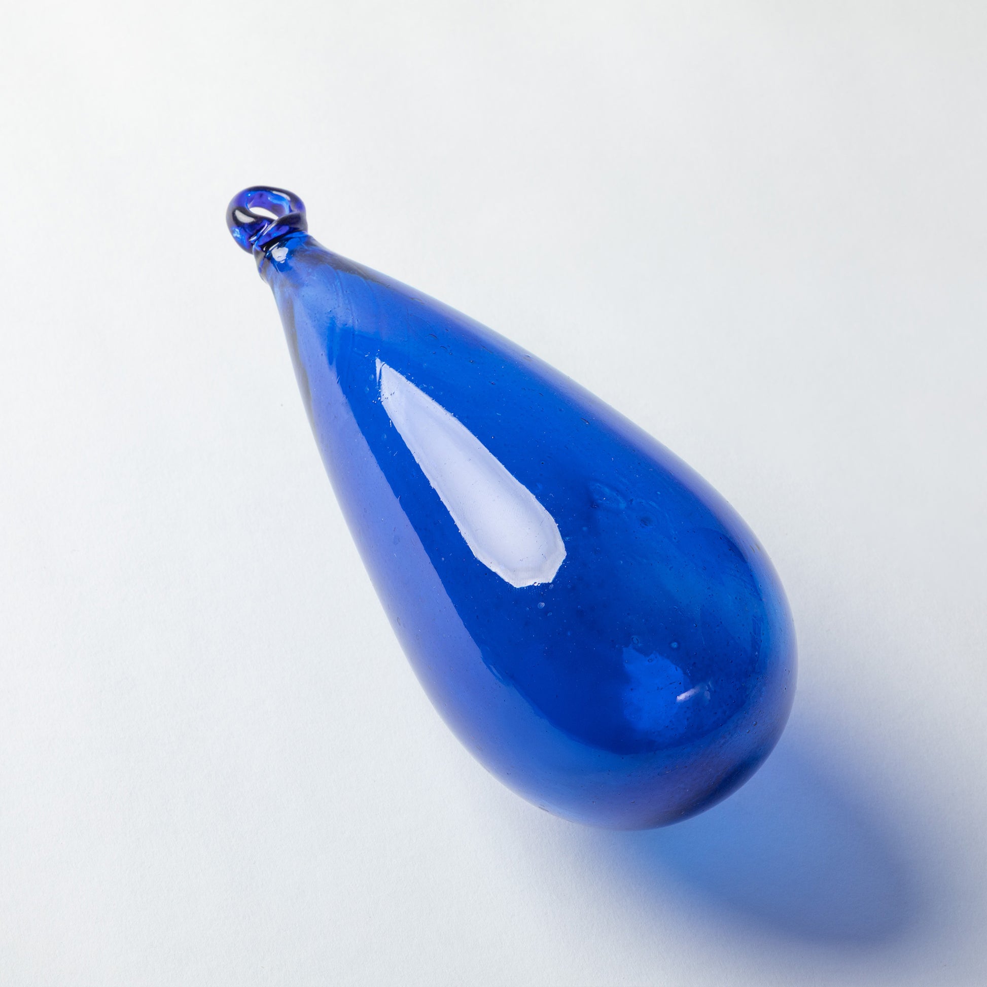 A teardrop-shaped cobalt blue glass pendant with a small loop at the top, shown on a clean white background with a soft shadow.