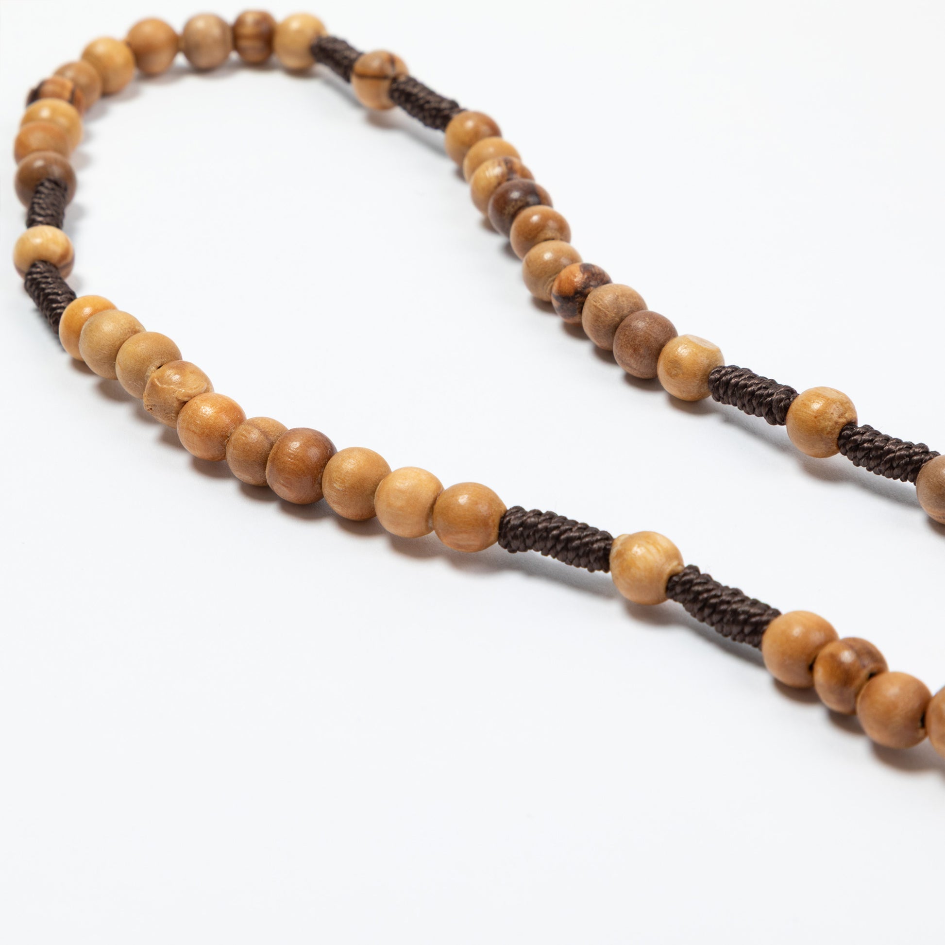 Necklace with wooden beads and brown cord on a white background