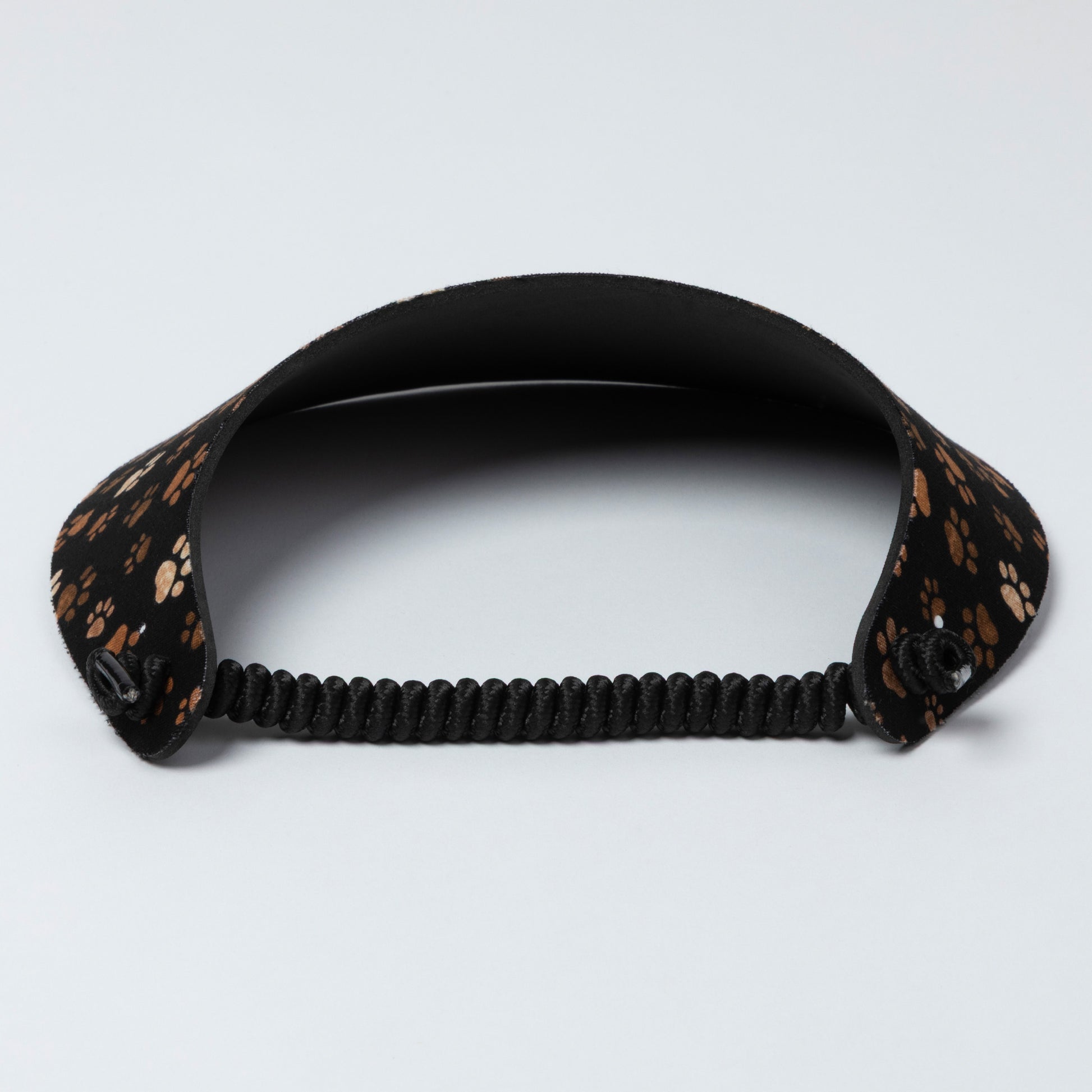Black visor with a patterned strap on a light gray background