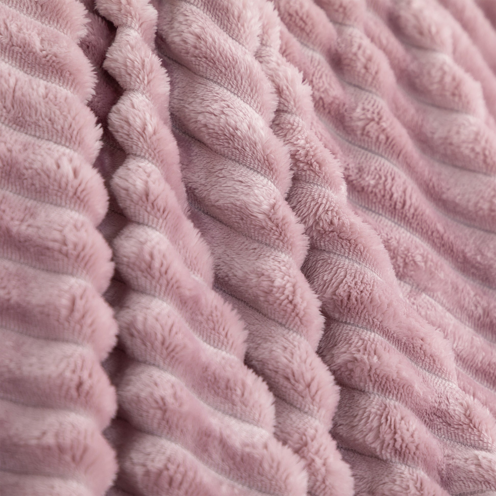 A close-up of a dusty pink textured throw blanket with a ribbed, corduroy-like plush surface.
