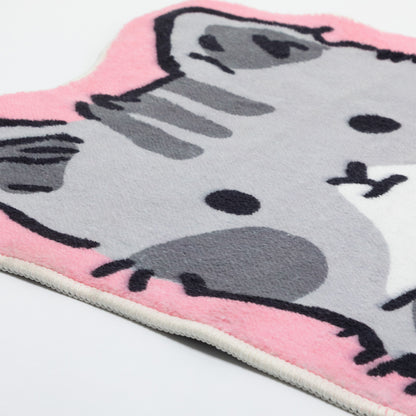 A close-up of a plush cat-face shaped mat in pink, white, gray, and black, photographed on a white background.