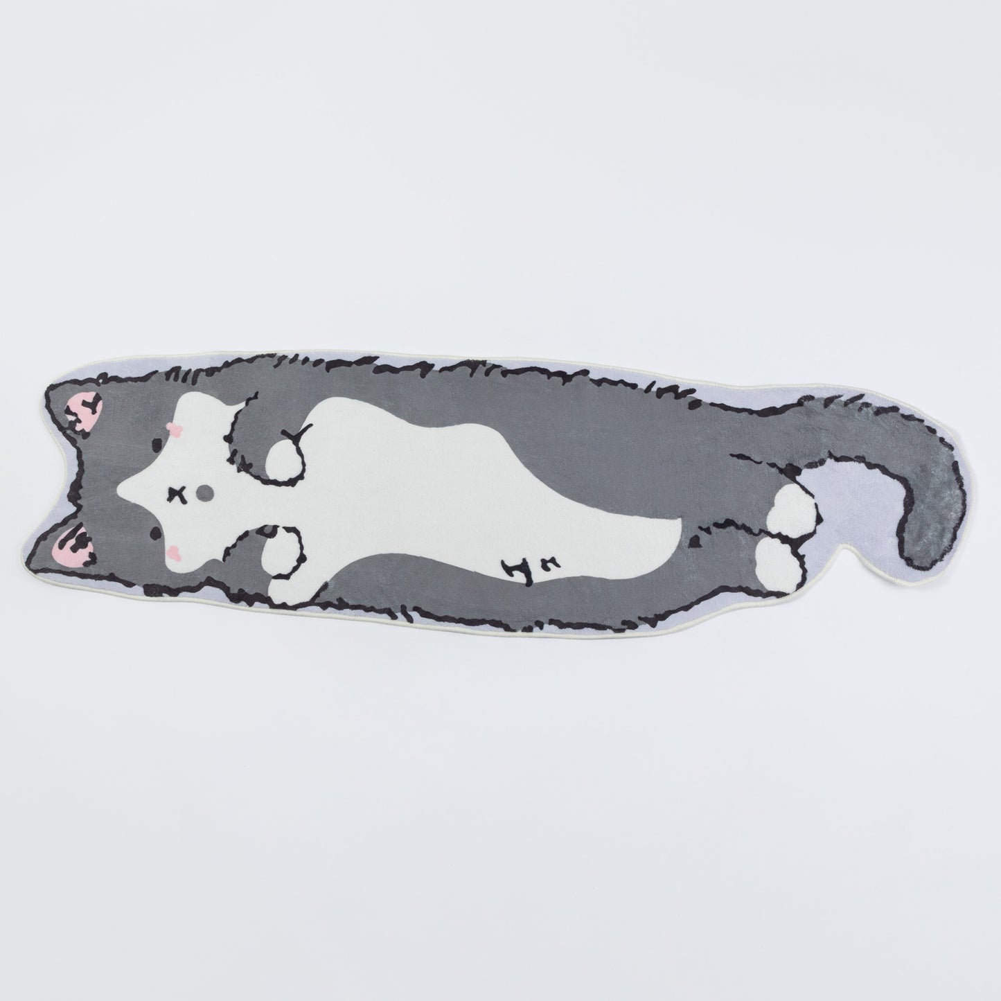 A die-cut plush cushion shaped like a sleeping gray and white cat, featuring pink inner ears and small black stitched facial details, shown on a plain light gray background.