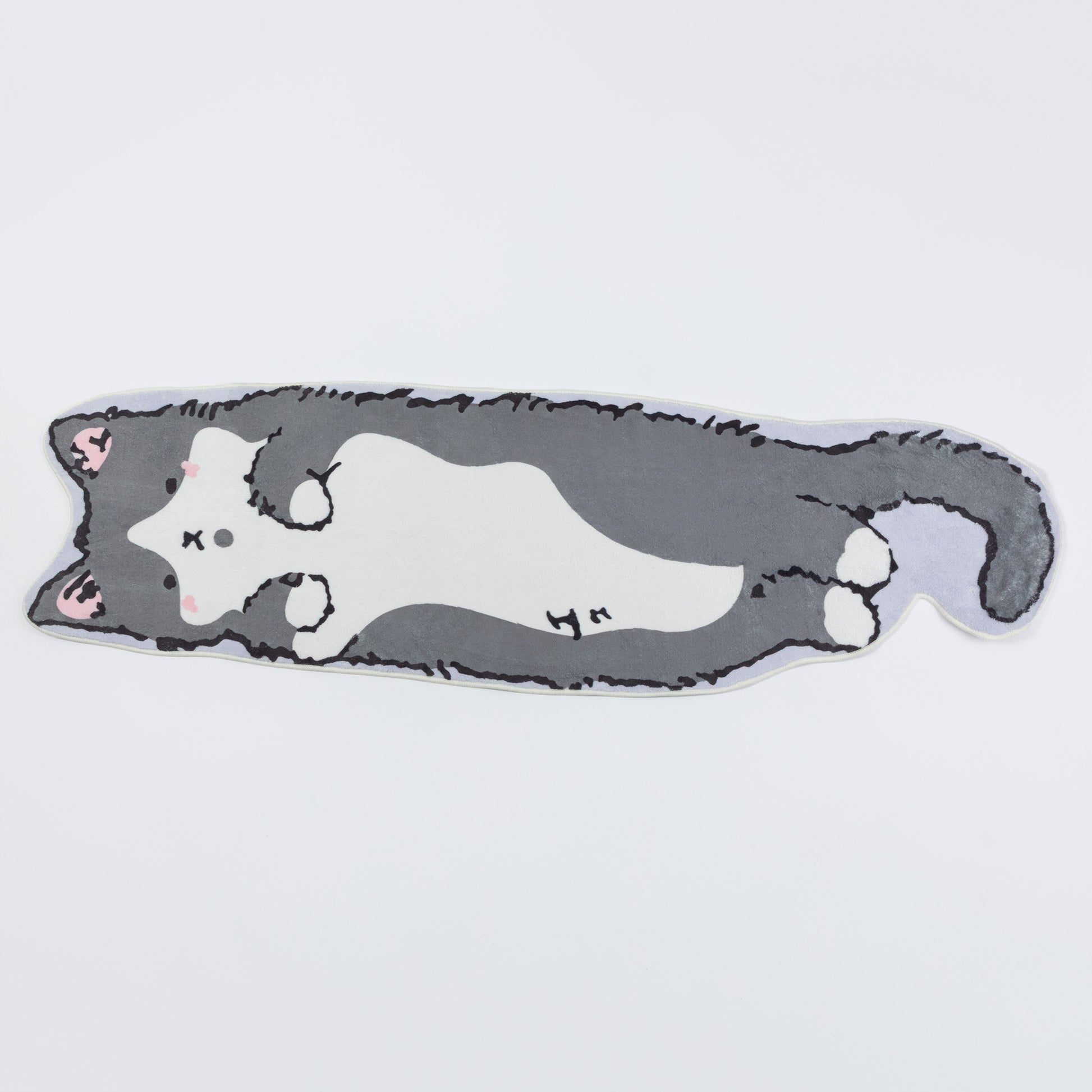 A die-cut plush cushion shaped like a sleeping gray and white cat, featuring pink inner ears and small black stitched facial details, shown on a plain light gray background.