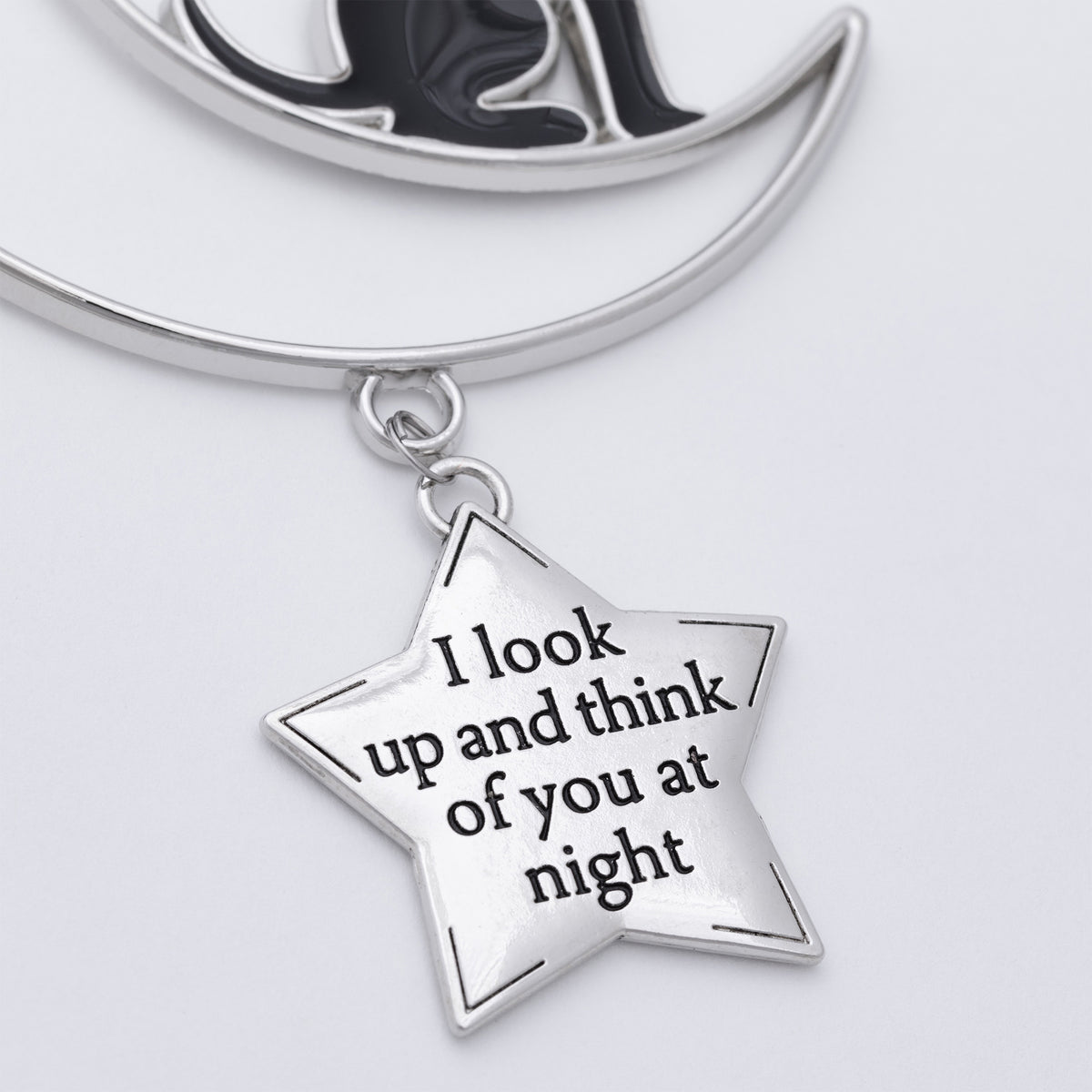 Silver crescent moon and star pendant necklace with a star charm engraved with the phrase 'I look up and think of you at night' on a light gray background.