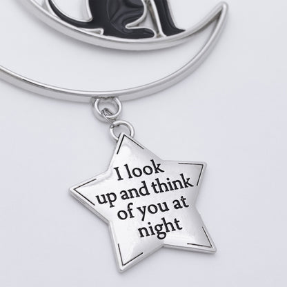 Silver crescent moon and star pendant necklace with a star charm engraved with the phrase 'I look up and think of you at night' on a light gray background.