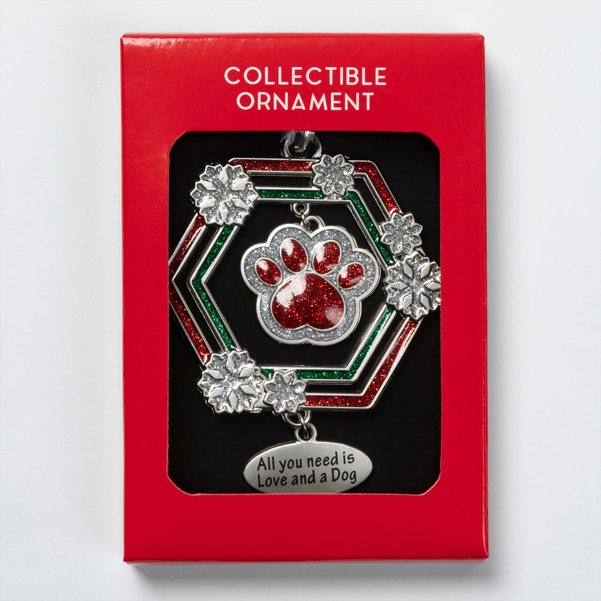 A collectible dog-themed ornament in its red gift box. The ornament features a silver-toned hexagonal frame with red glitter accents, silver snowflake details, and a central red glitter paw print.