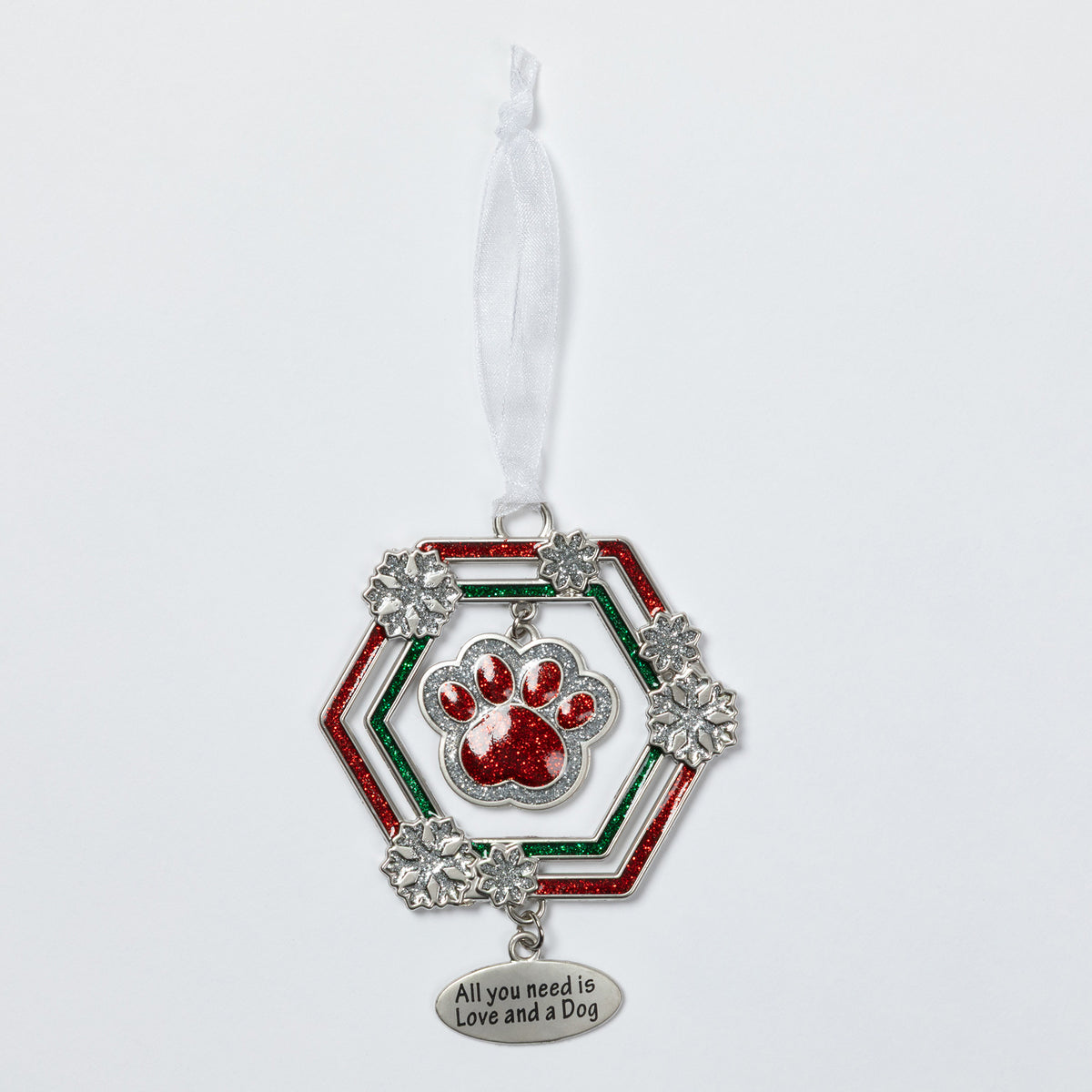 A silver-toned dog ornament featuring a red glitter paw print in the center, surrounded by a red and green glitter hexagonal frame with silver snowflake accents. A white ribbon is tied to the top, and a dangling silver tag at the bottom reads 'All you need is Love and a Dog'.