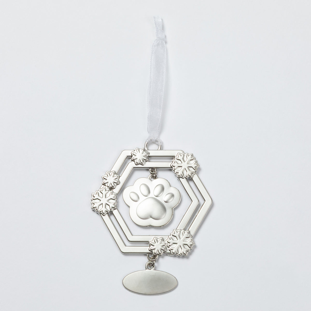 A silver-toned metal pet memorial ornament featuring a central paw print, surrounded by a hexagonal frame with snowflake-like accents and a hanging oval plate, suspended from a white ribbon on a light gray background.