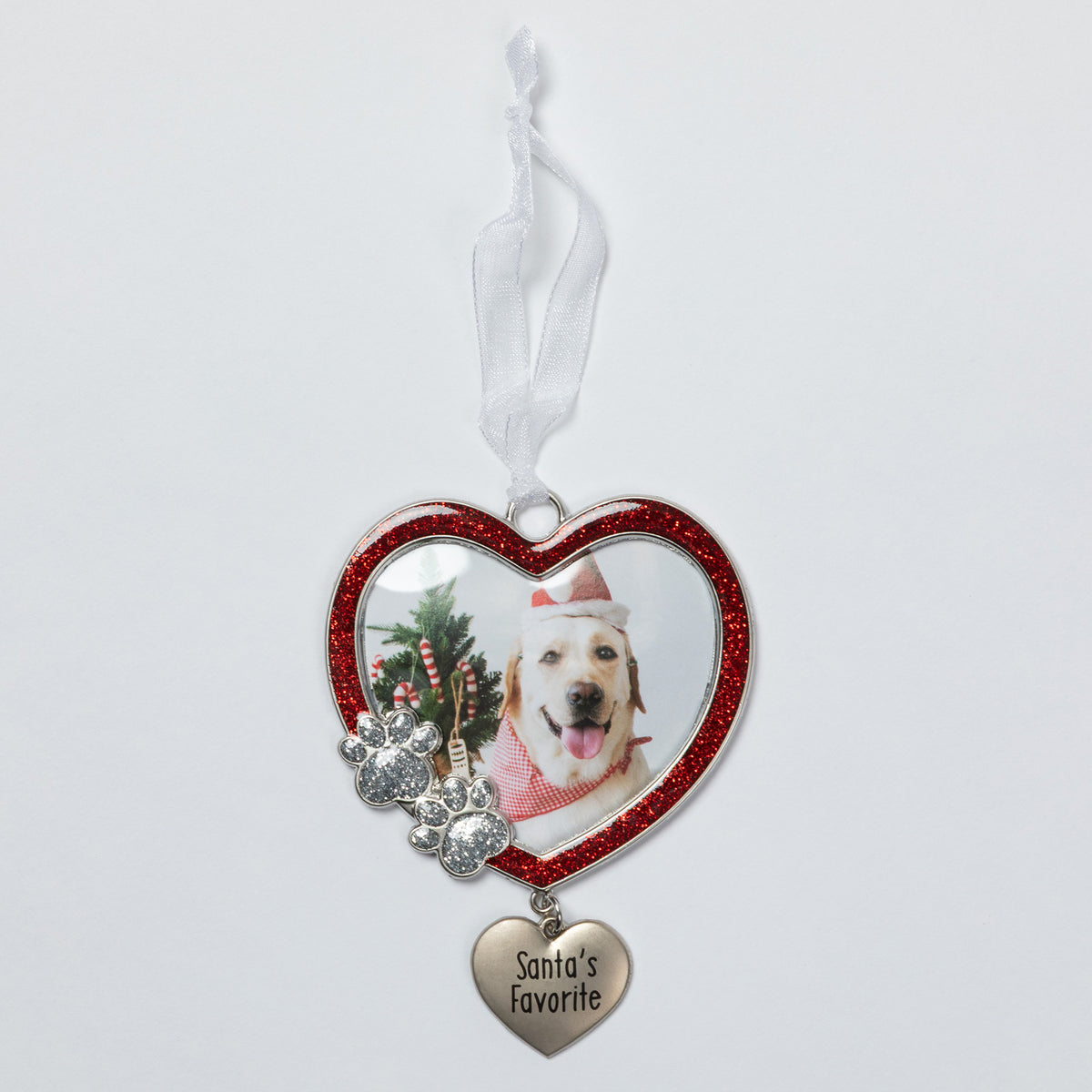 A heart-shaped pet photo ornament with a red glitter border, featuring a custom photo of a dog, silver paw prints, and a dangling heart charm engraved with 'Santa's Favorite' on a white ribbon.