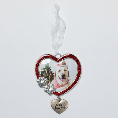 A heart-shaped pet photo ornament with a red glitter border, featuring a custom photo of a dog, silver paw prints, and a dangling heart charm engraved with 'Santa's Favorite' on a white ribbon.