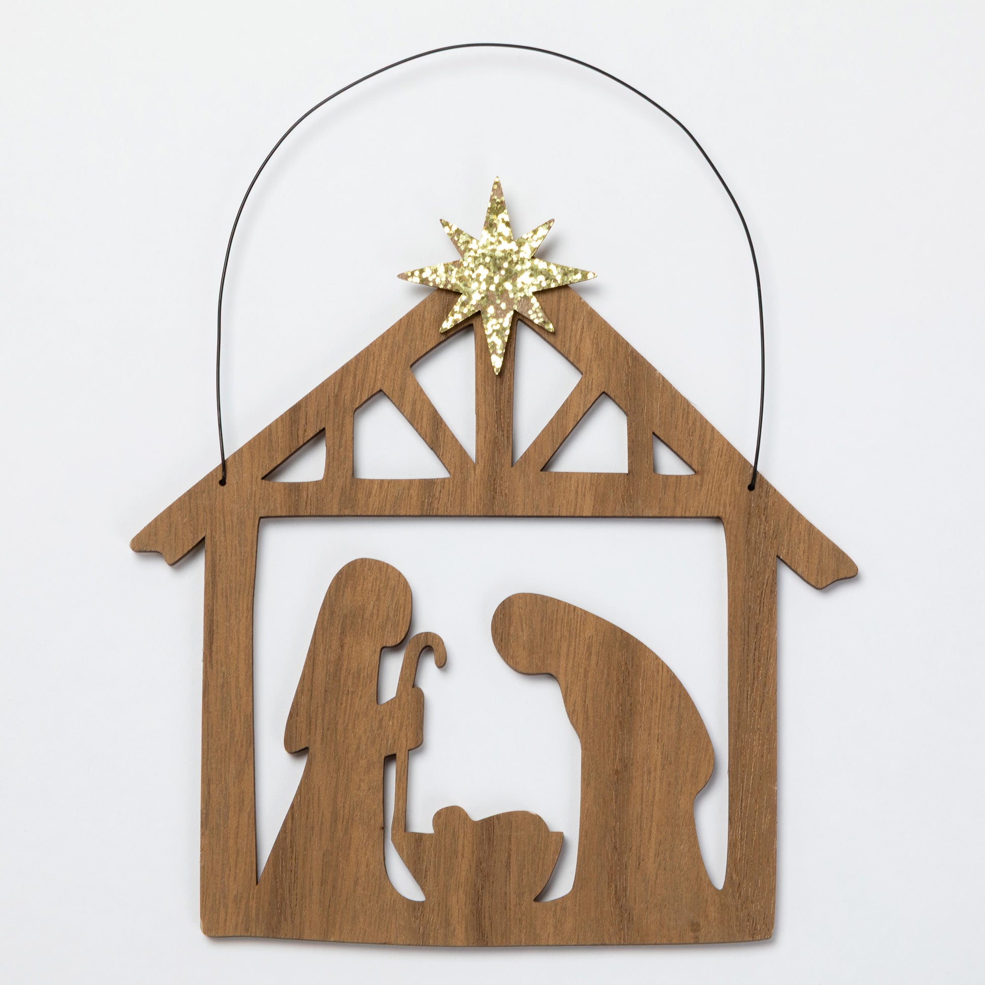 A wooden Nativity scene ornament with a star on top, shown on a plain light background.