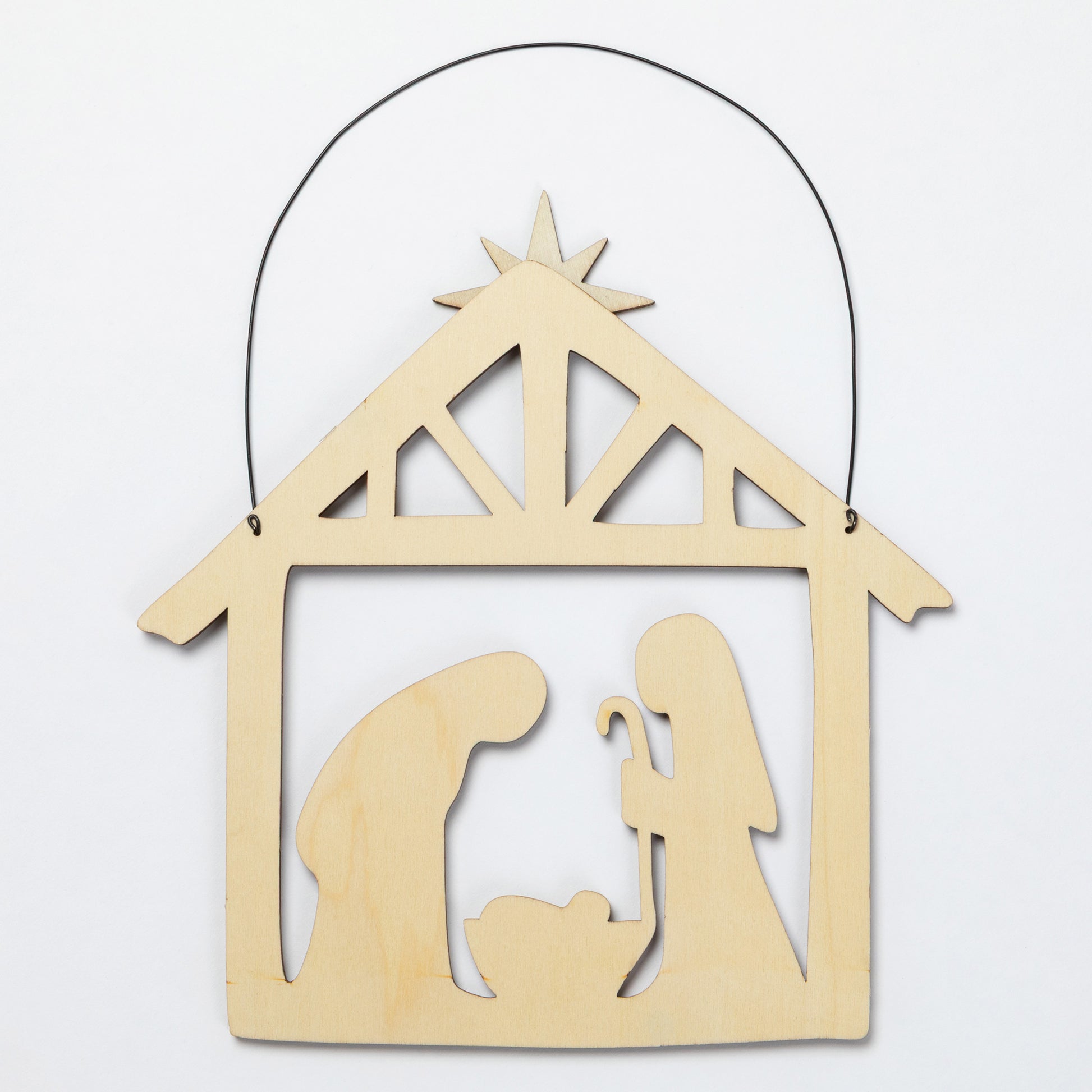 A light natural wood hanging nativity scene ornament with a black wire hanger, featuring silhouettes of Mary, Joseph, and baby Jesus under a star on a plain white background.