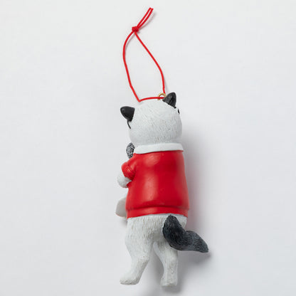 A small cat-shaped hanging ornament shown from the back, with a white body, black ears and tail, and a red sweater, suspended by a red string against a plain light background.