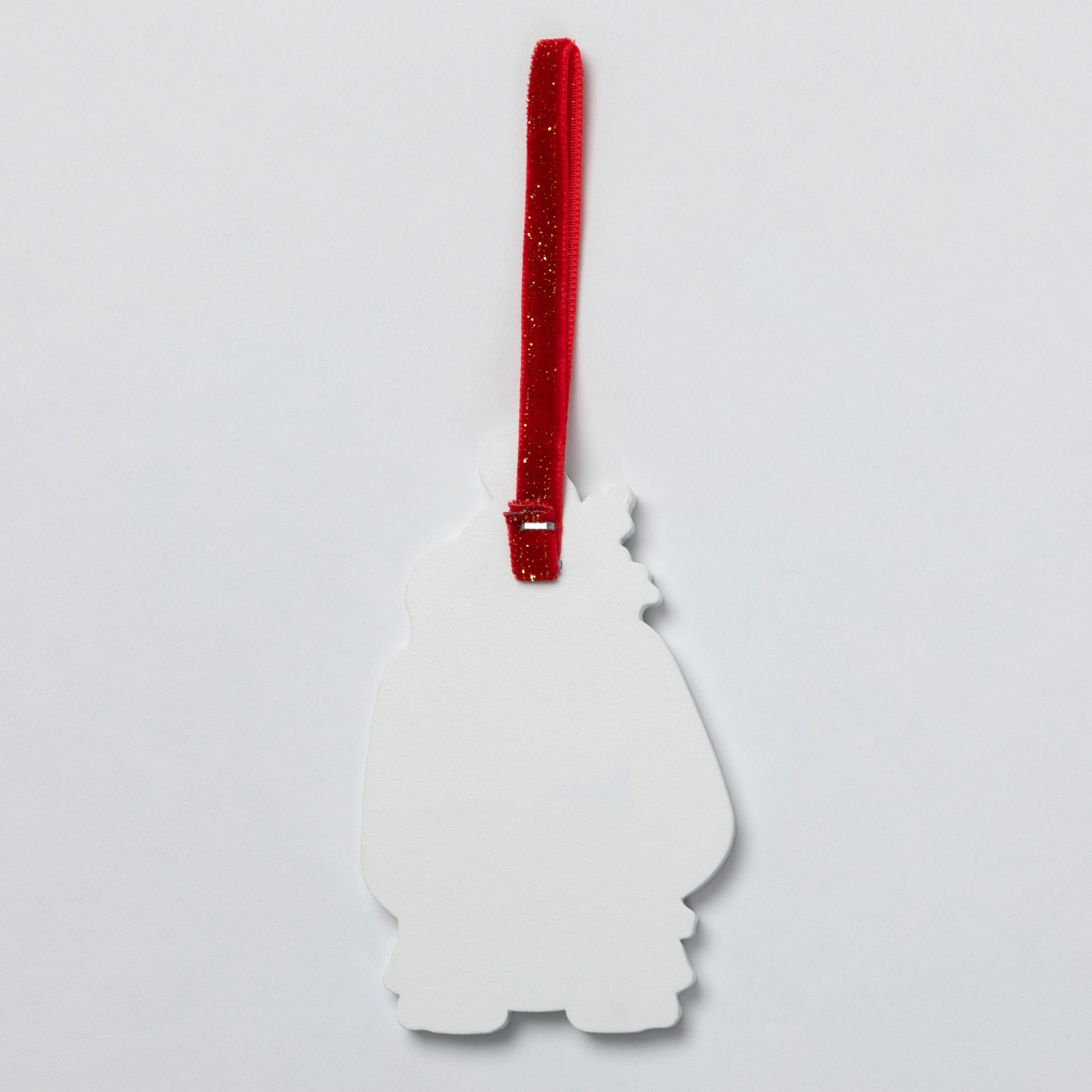 The plain white back of a Christmas ornament with a red glittery hanging ribbon, shown against a plain light gray background.