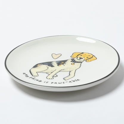 A white ceramic plate with a black rim, featuring a cartoon illustration of a beagle puppy with the text 'anything is paws-able' and a small heart on a white background.