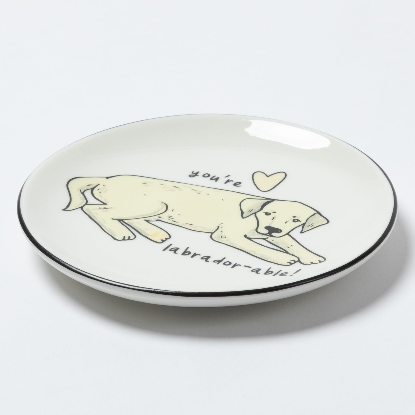A white ceramic plate with a black rim, featuring a hand-drawn illustration of a yellow Labrador puppy with the text 'you're labradorable!' and a small heart.