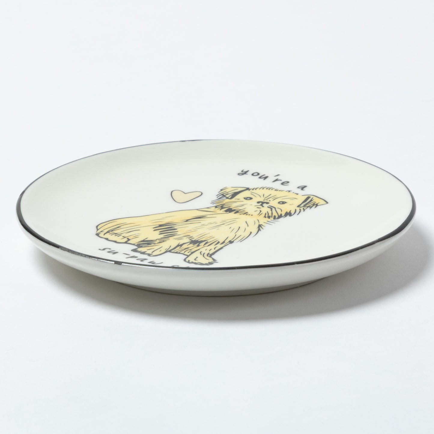 A white ceramic plate with a black rim, featuring a hand-drawn illustration of a yellow dog with the text 'you're a' above it and 'in love' below it, shown on a clean white background.