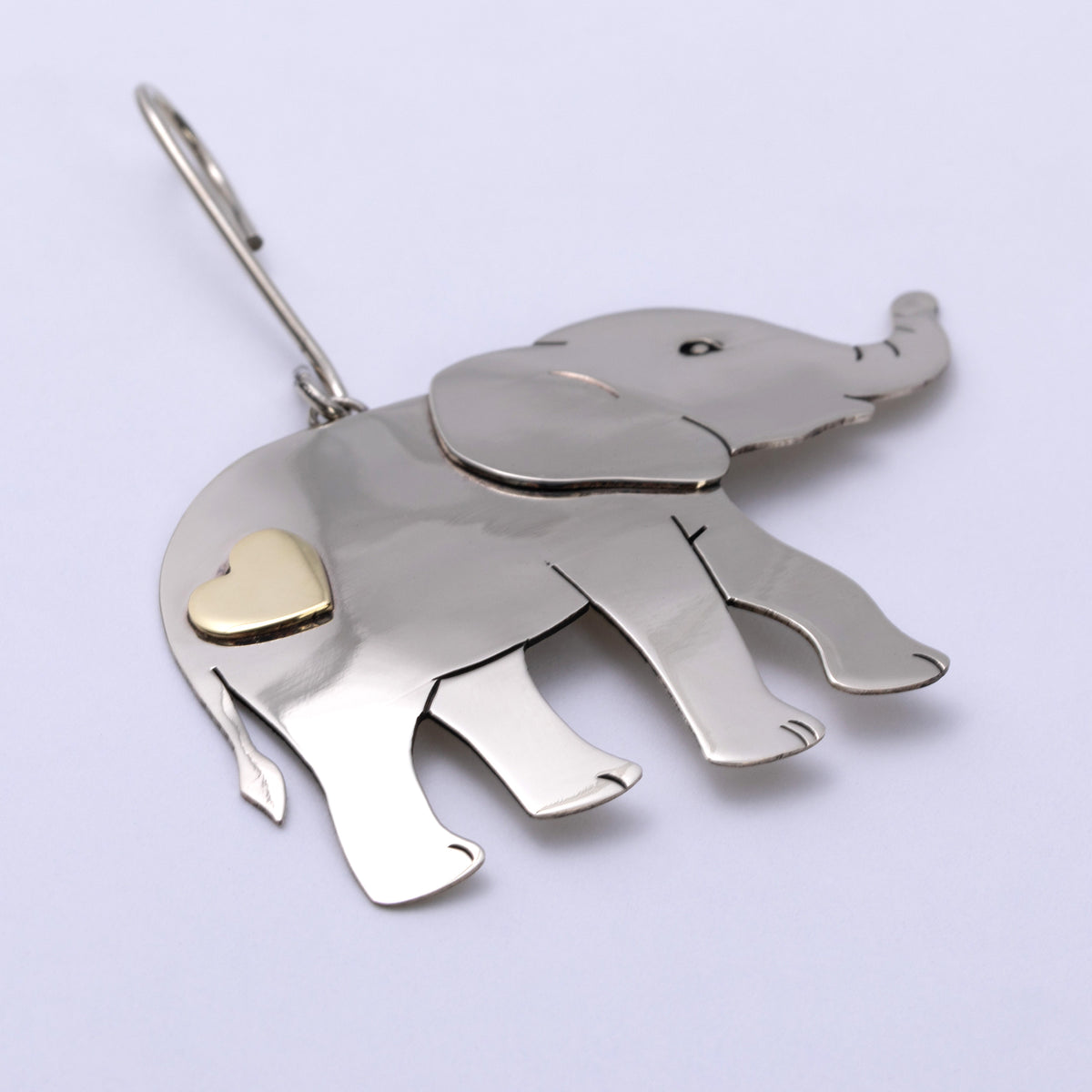 A silver elephant-shaped ornament with a small gold heart accent on its side, shown on a plain light background.