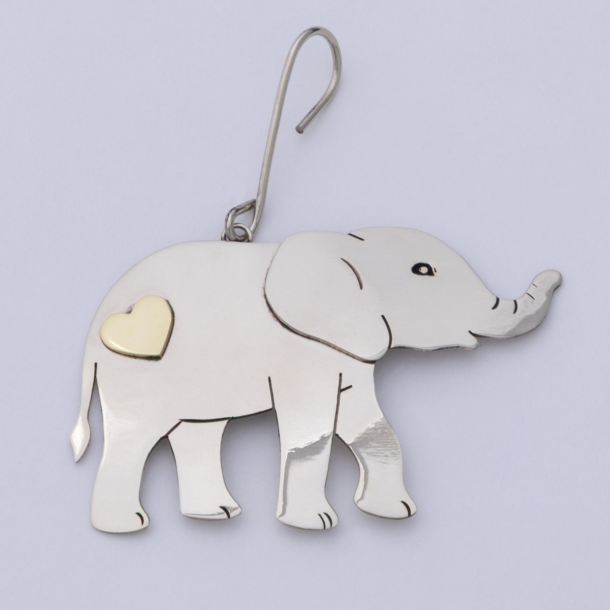A silver elephant-shaped ornament with a small gold heart accent on its side, shown on a plain light background.