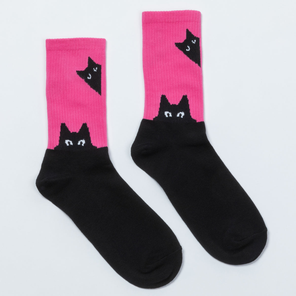 A pair of crew socks with a black and bright pink color-blocked design, featuring a black cat peeking out from the top on the pink section.