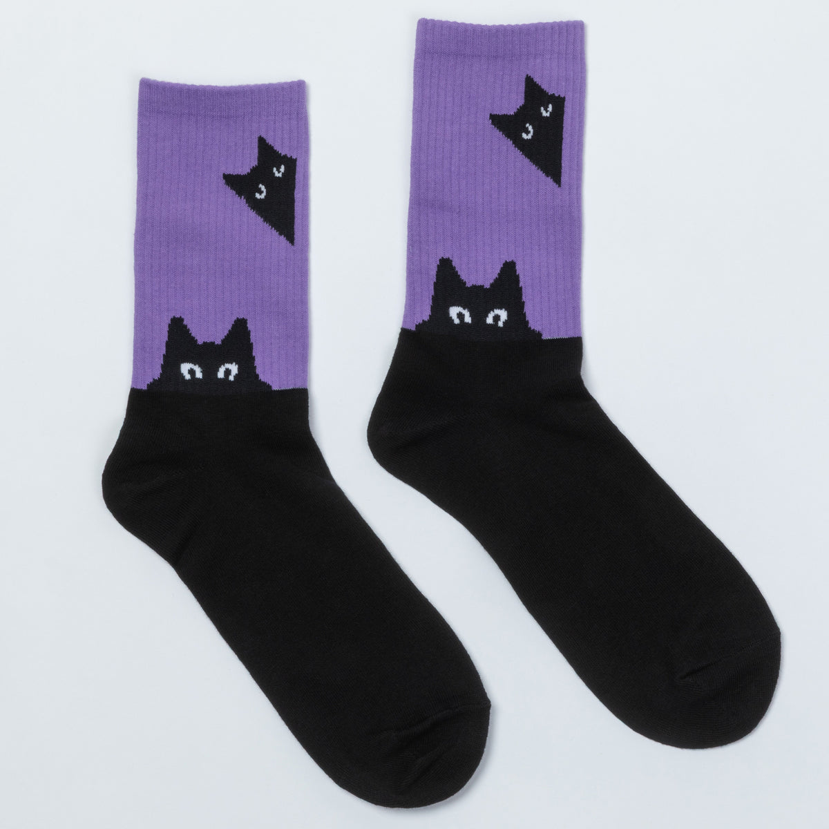 A pair of crew socks with a split design: the upper portion is lavender purple with a black cat head graphic, and the lower portion is solid black.