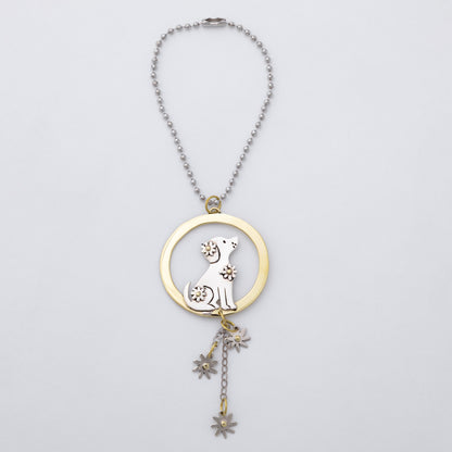A silver and brass car charm featuring a circular pendant with a gold-toned ring, a silver dog silhouette, and dangling flower charms, shown on a light gray background.