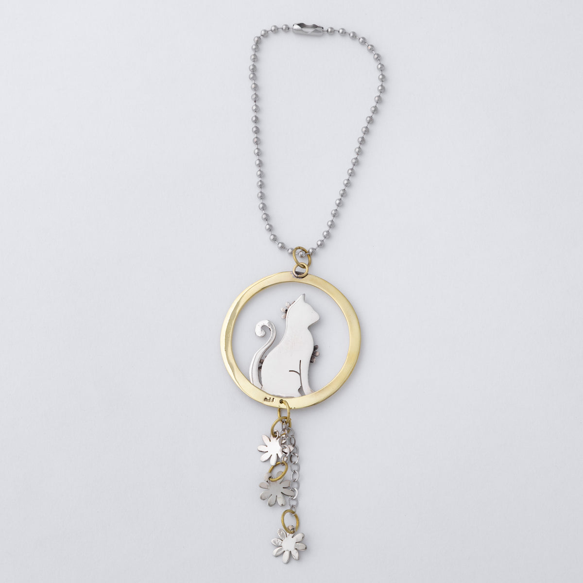 A silver ball chain car charm featuring a circular pendant with a silver cat silhouette and flower details, accented by a gold-tone ring and matching dangling flower charms, shown on a light gray background.